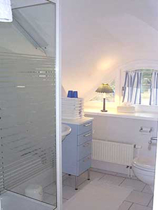Das kleine aber helle Bad des Appartments des Darsser Teekaten. Neben der Dusche ist das Waschbecken und die kleine Kommode.