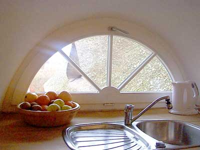 Der K&uuml;chenbereich der Ferienwohnung liegt an einer Gaube mit einem kleinen Sprossenfenstermit idyllischem Blick auf das Reetdach.