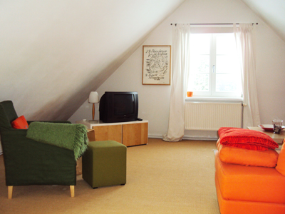 Wohnbereich der Ferienwohnung. Warme Farben. Grosses Sofa. Indirekte Beleuchtung.
