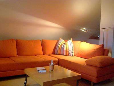 Wohnbereich der Ferienwohnung. Warme Farben. Grosses Sofa. Indirekte Beleuchtung.